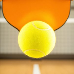 Pickleball player hitting ball on court.