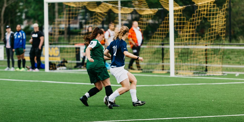 women playing soccer on green field during daytime